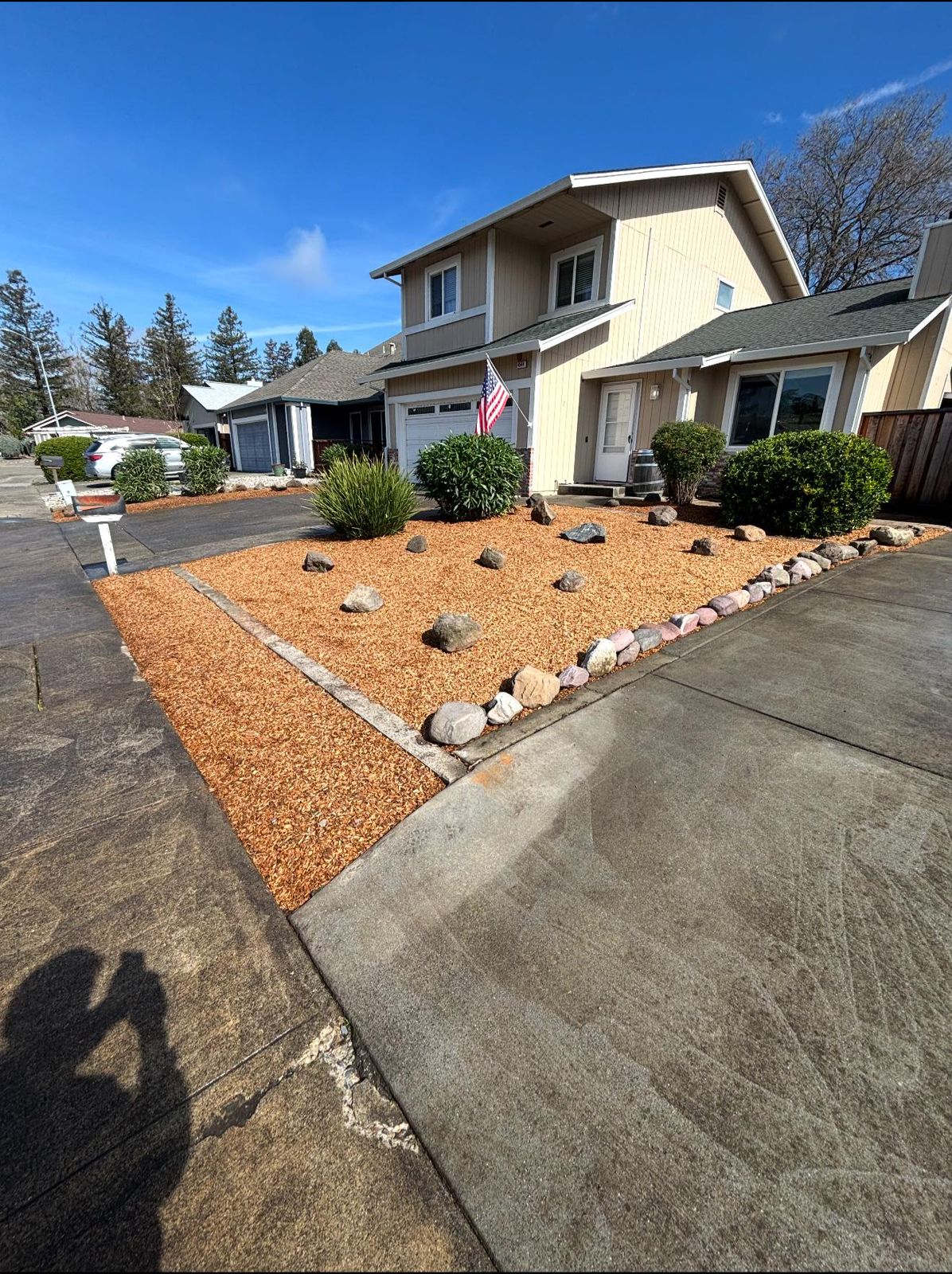 Front yard with fresh bark mulch, rock border and shaped shrubs