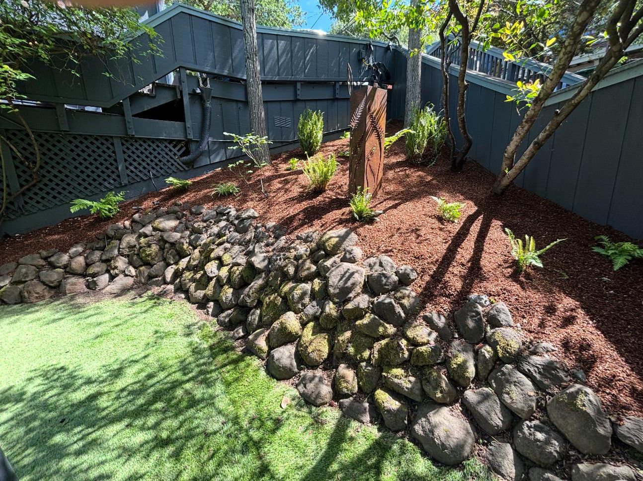 Backyard slope with mulch beds, ferns and a stone retaining wall